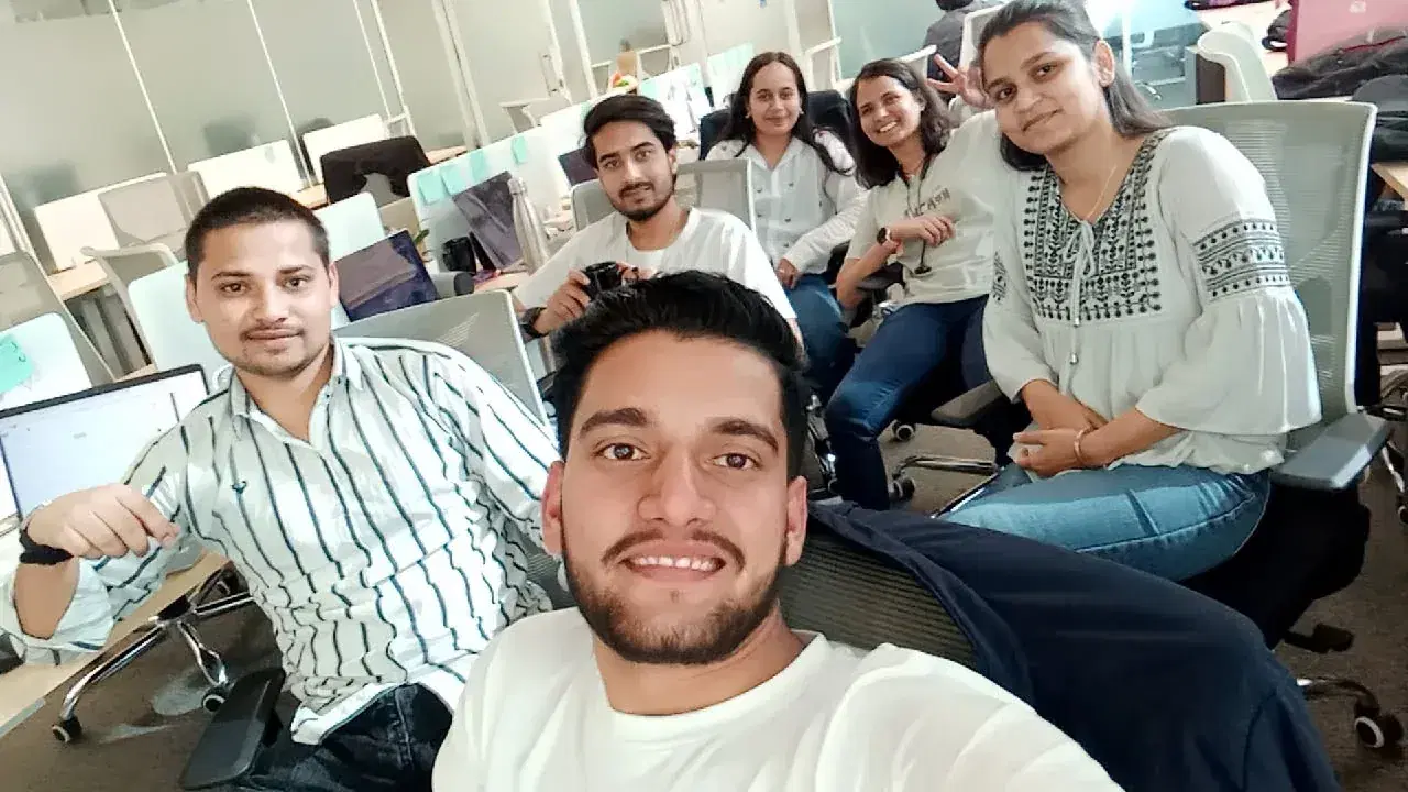 A selfie with teammates at their desks in the open-plan office