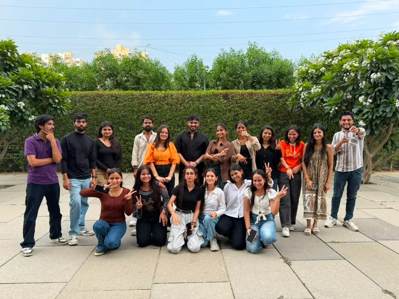 The full ANSI team together outdoors in front of a flowering hedge