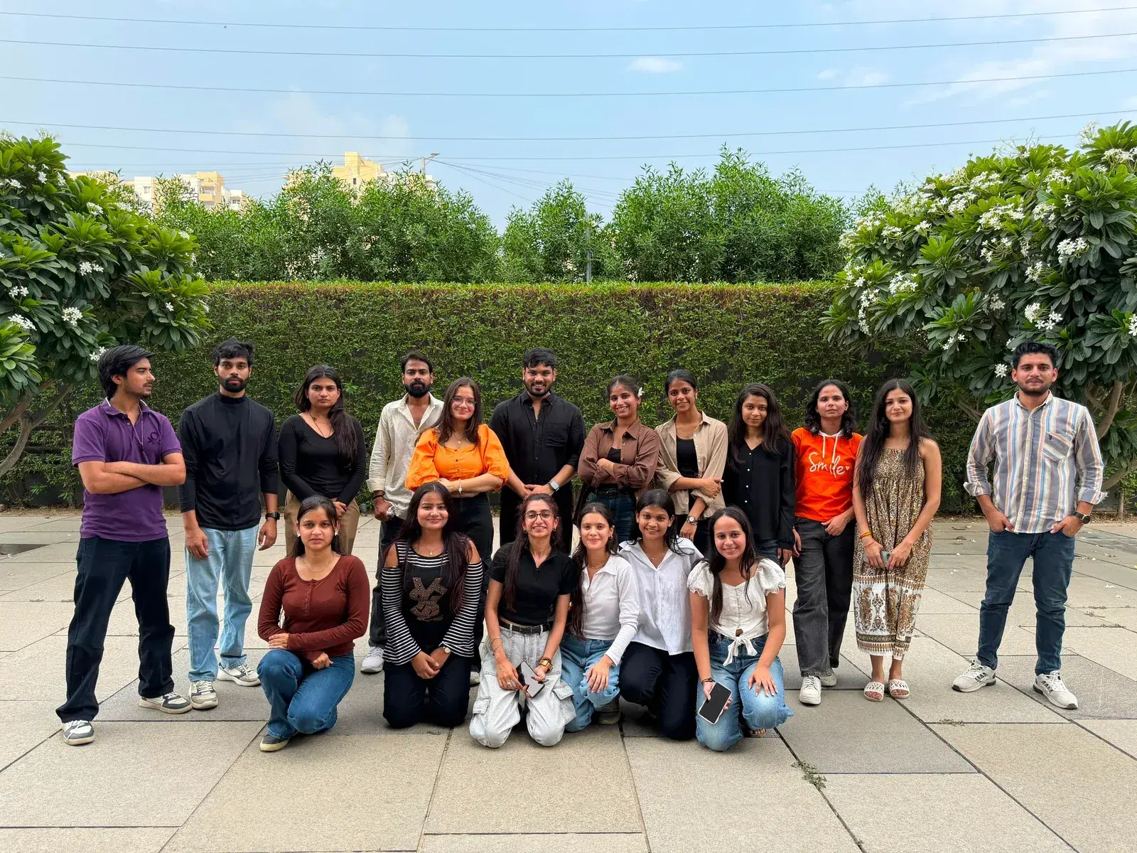 The full ANSI team together outdoors in front of a flowering hedge